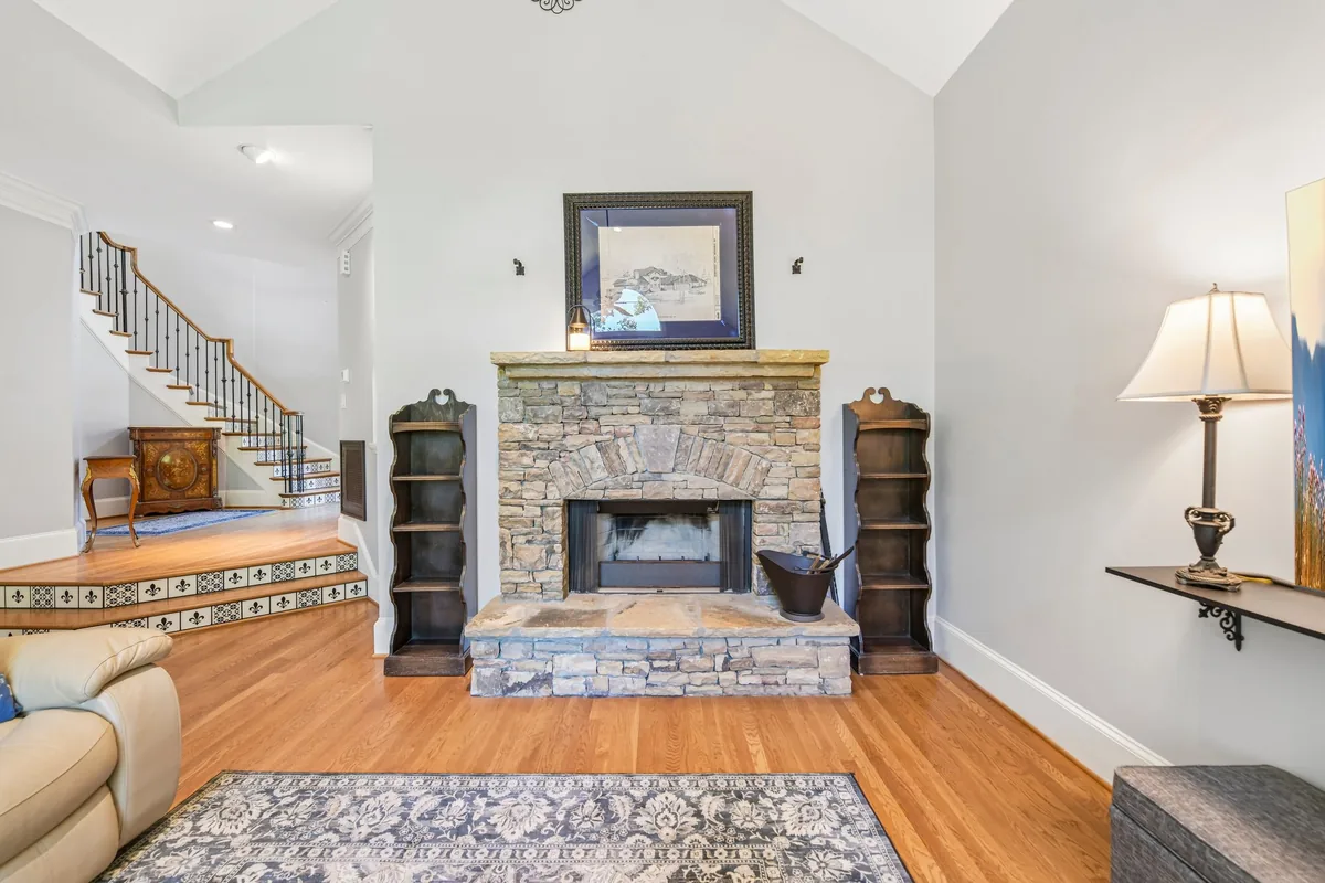 Stone fireplace wall with a wood mantel and flanking windows